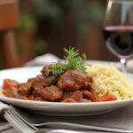 Delicious bifes de cebolada served with rice and wine for a traditional Portuguese meal.